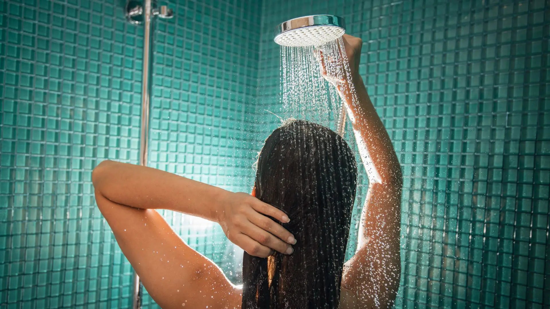 Woman in shower with green tiles